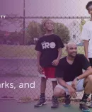 two smiling young people and an adult on a basketball court